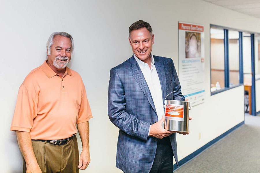 Rep. Peters (right) holds a can of Surface Optics Corporation’s spectrally tailored paint, next to Bill Mohar, Director of Commercial Instrument Sales (left).